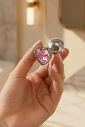 Metal plug with pink heart crystal - hand held close-up view